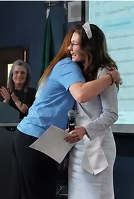 Ashley Loncon hugs Lilac Princess Chloe Nelson during the surprise classroom recognition
